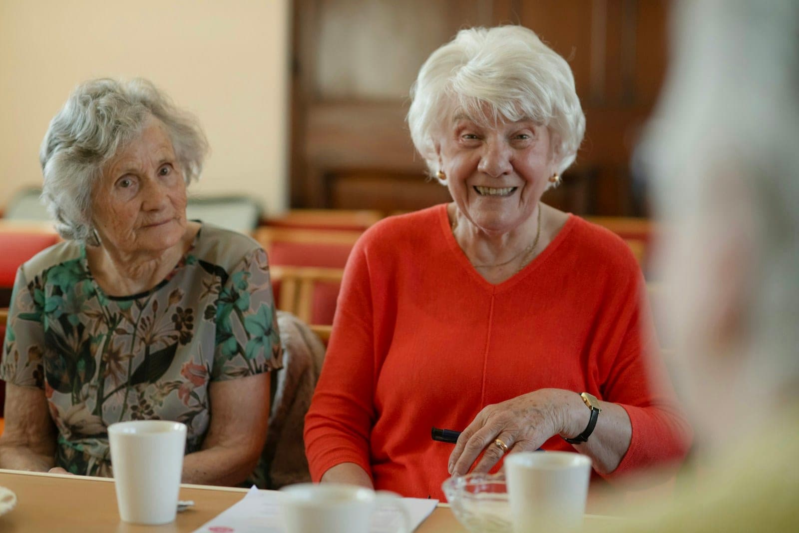 Two older women laughing together at a table